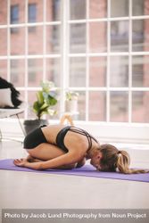 Relaxed woman in child pose on yoga mat 5zYDN0