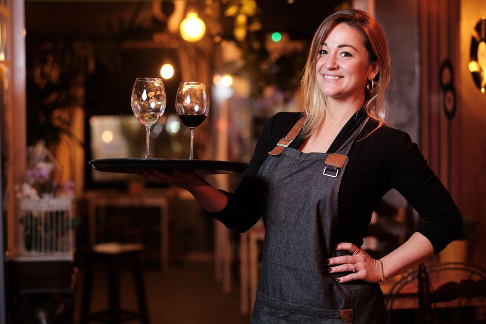 Cheerful waitress holding tray with wineglasses