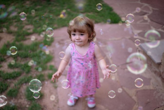 Joyful girl playing with colorful bubbles in grass