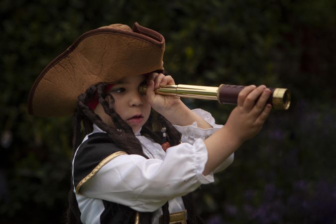 Girl in Pirate costume looking through telescope