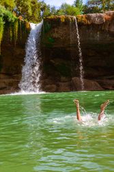Legs in clean water near waterfall