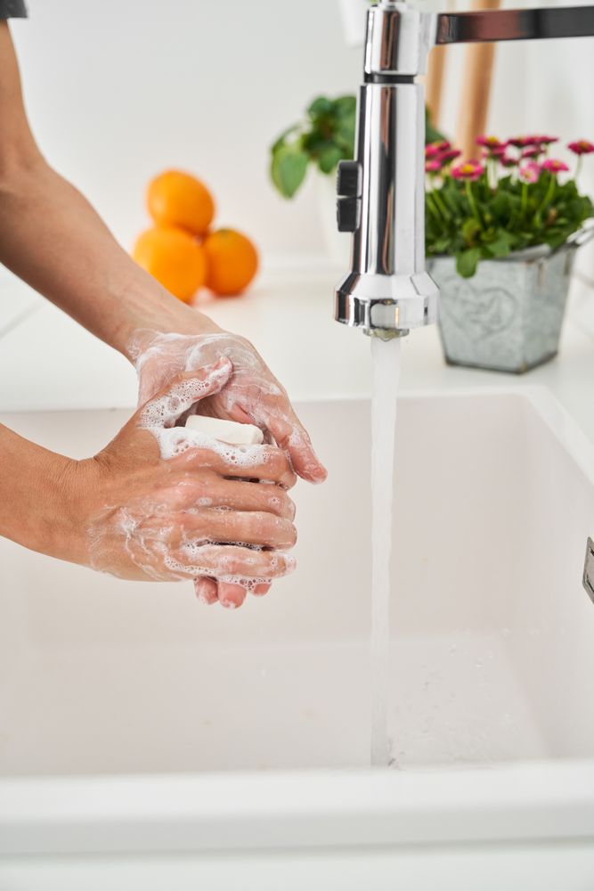 Person washing hands with soap and water in basin