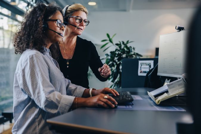 Two mature women working as a team at office desk