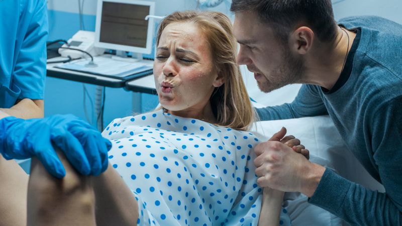 In the Hospital Close-up on Woman in Labor Pushes to Give Birth, Obstetricians Assisting, Husband Holds Her Hand