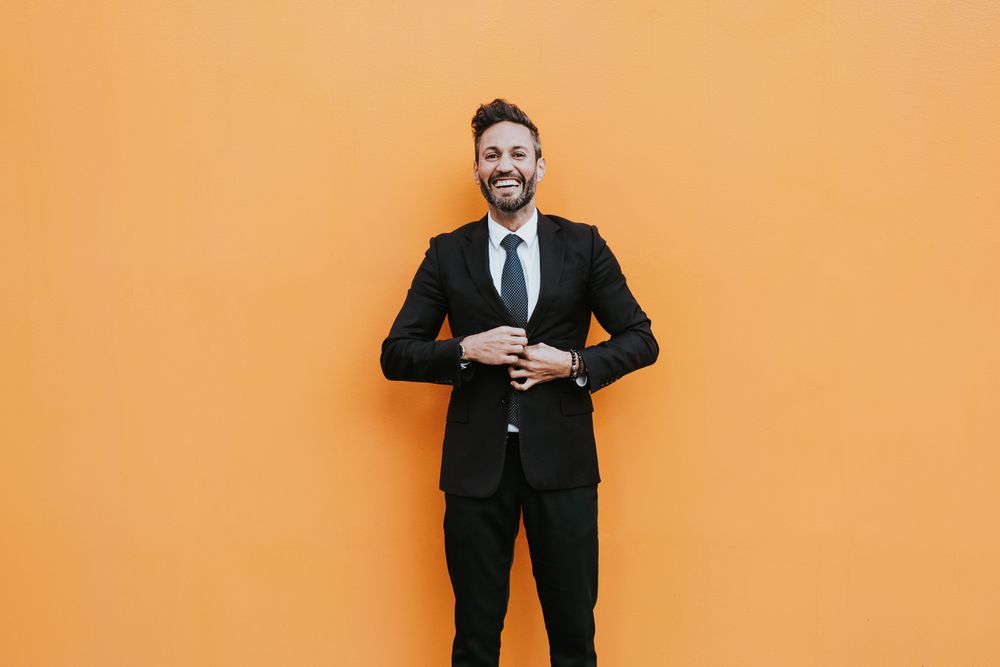 Adult stylish man in costume near orange wall