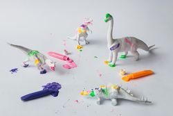 Plastic dinosaur splattered with different colors of paint