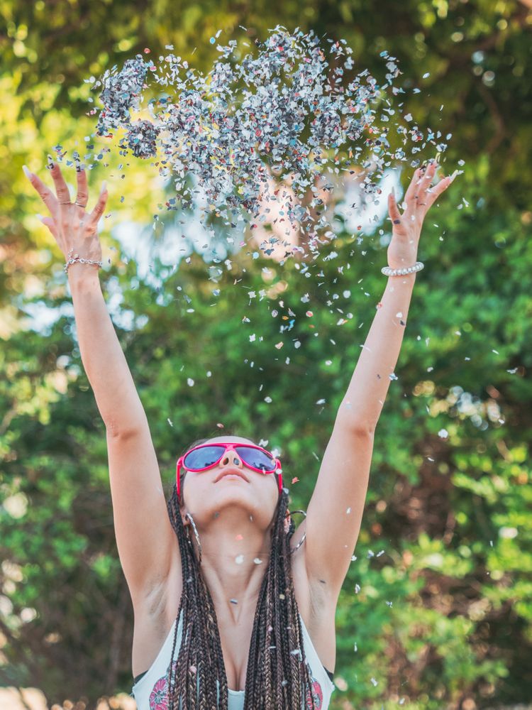 Happy young woman throwing confetti during party