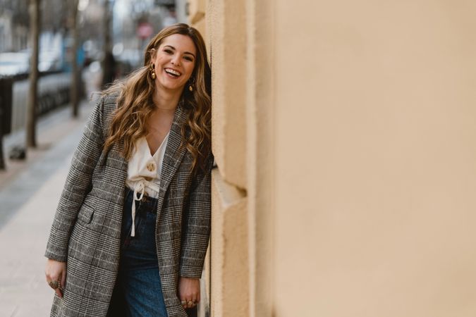 Laughing woman leaning on wall on street