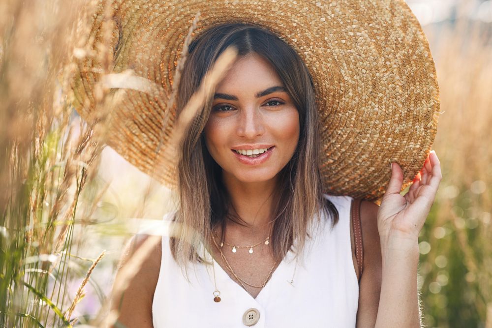 Content woman in field wearing a large straw hat