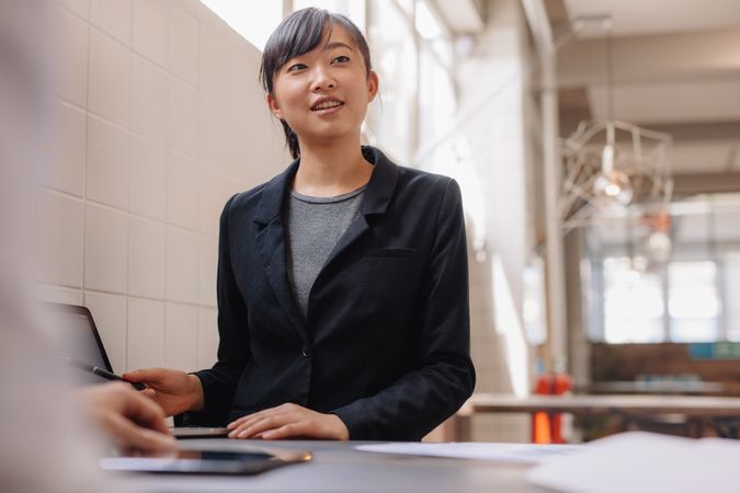 Confident young Asian executive presenting to coworkers