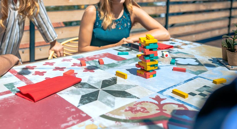 tower over table with unrecognizable people playing in a rooftop party