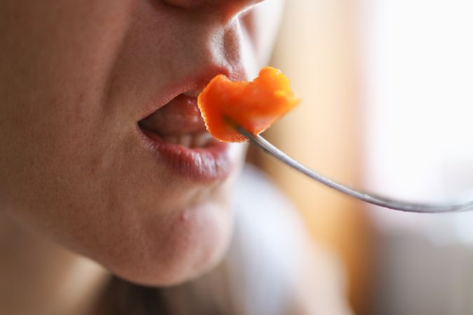 Nourishing Bite: Woman Eating Carrot as a Vitamin-Packed Nutritious Snack.