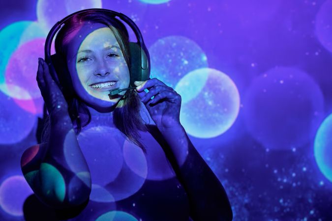 Cheerful woman with headset under colorful illumination