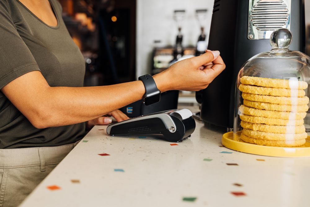 Person in bakery of coffee shop paying with a smart watch
