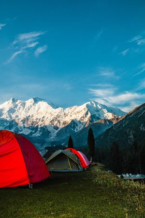 People camping facing snow capped mountains in Pakistan