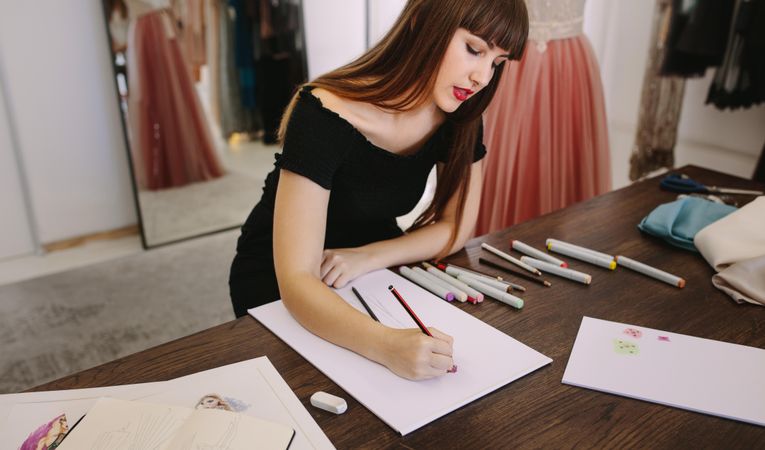 Fashion designer making a drawing in her cloth shop