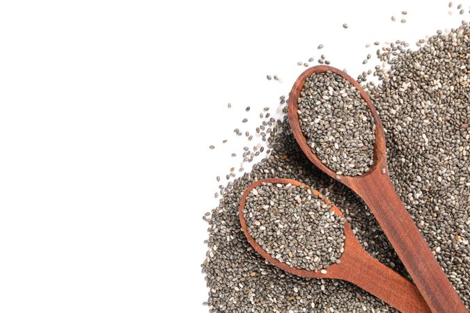 Chia seeds and wooden spoons isolated on blank background