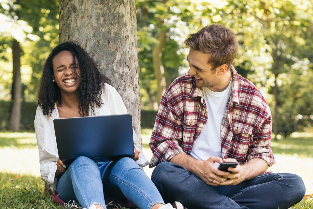 Multiracial couple studying in the park with laptop