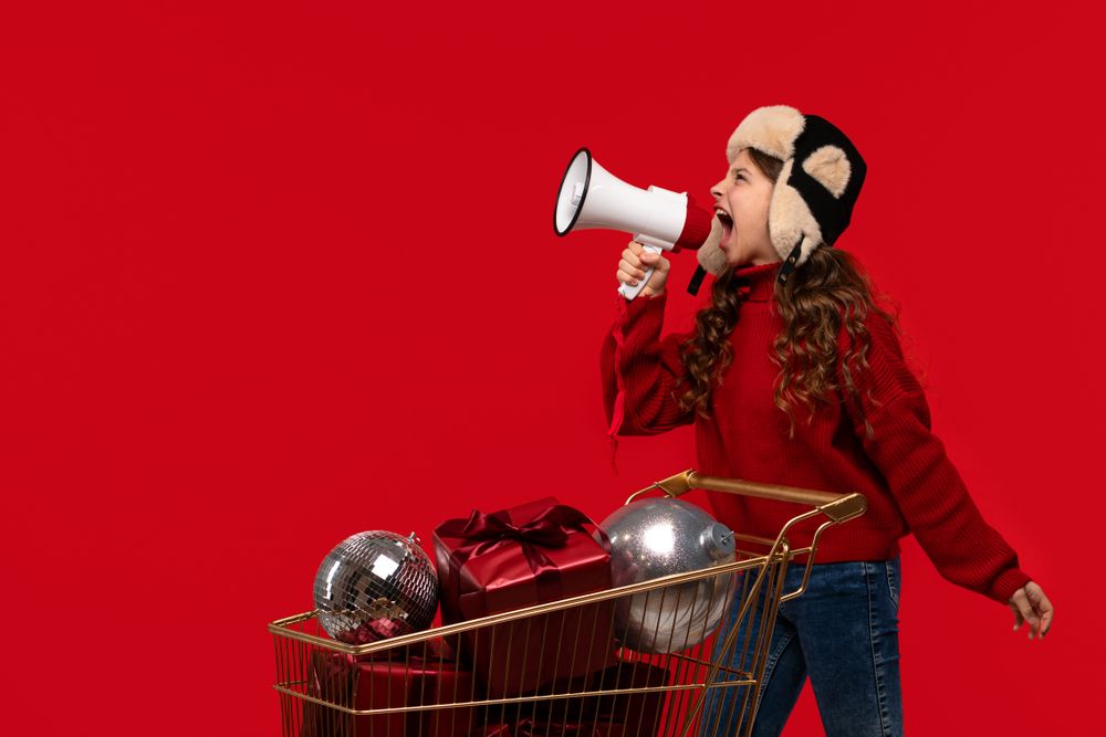 Excited girl in red sweater and hat shouts into megaphone