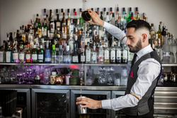 Bartender pouring a cocktail into shaker