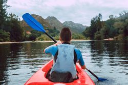 Female kayaking with paddle in raised hands