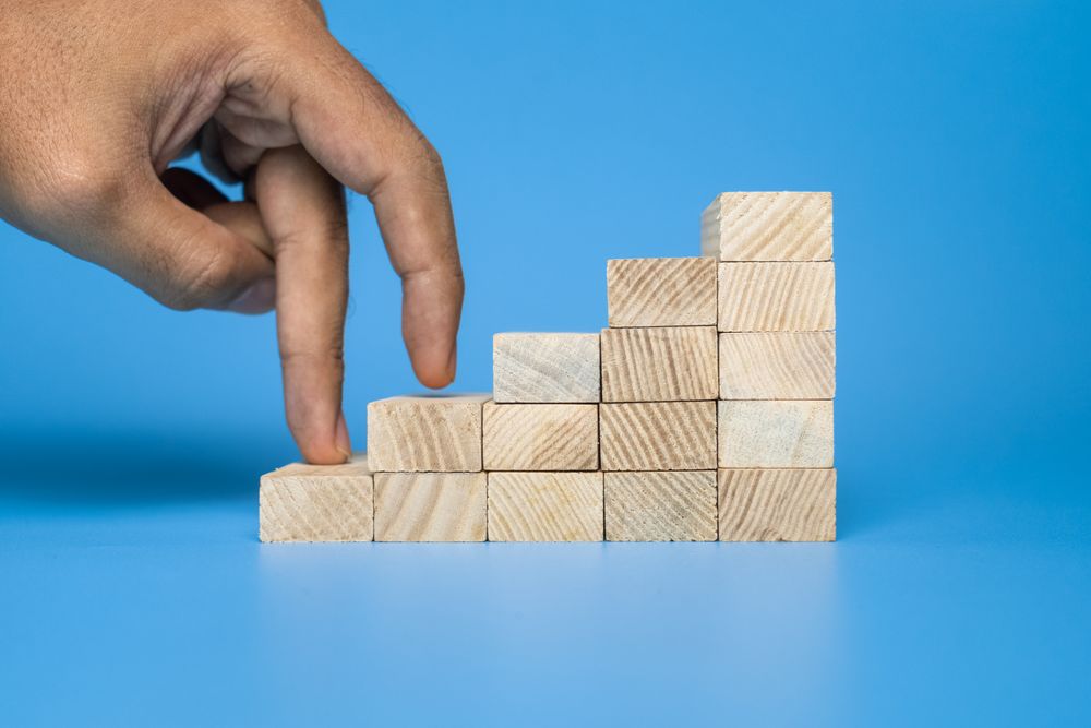 male hand walk on stairway wooden blocks isolated on blue background