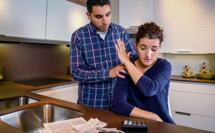 Woman holding up hand to keep man away as they have conflict about bills