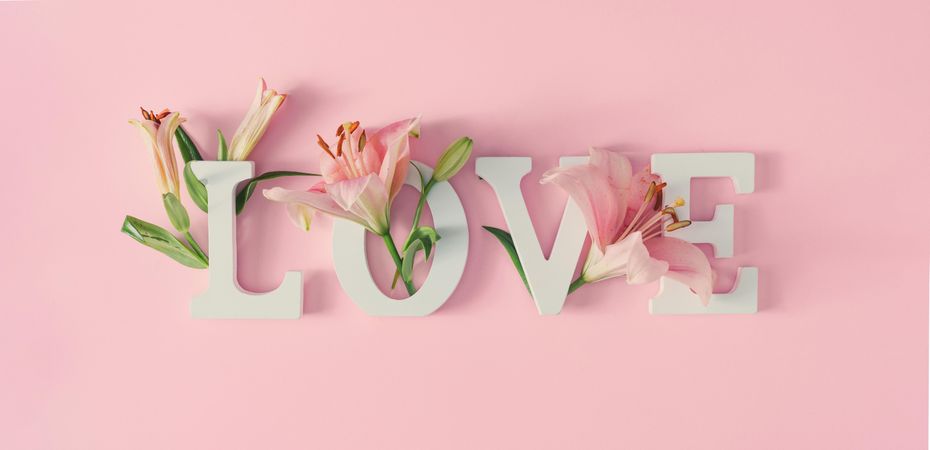 “Love” written on pink background with spring flowers