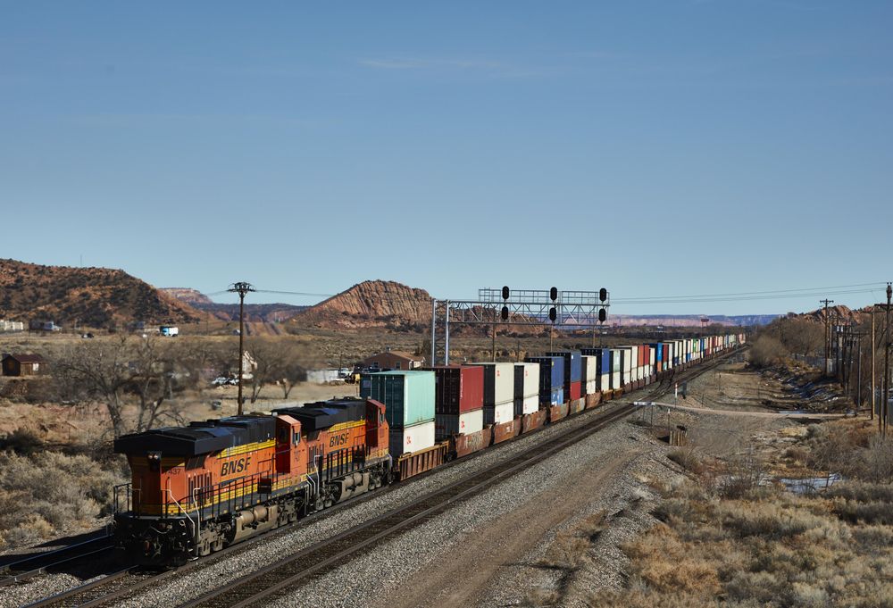 Two heavy diesel engines pull a long freight train into Gallup, New Mexico