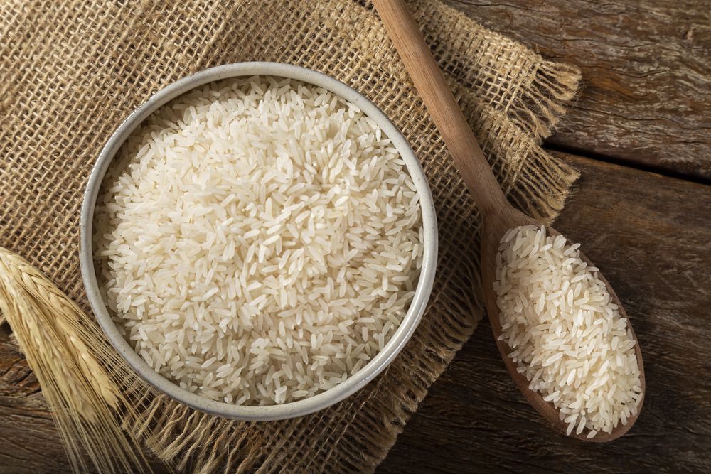 Rice in a ceramic bowl on brown wooden background.