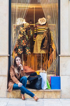 Content young woman in casual outfit resting on street after shopping
