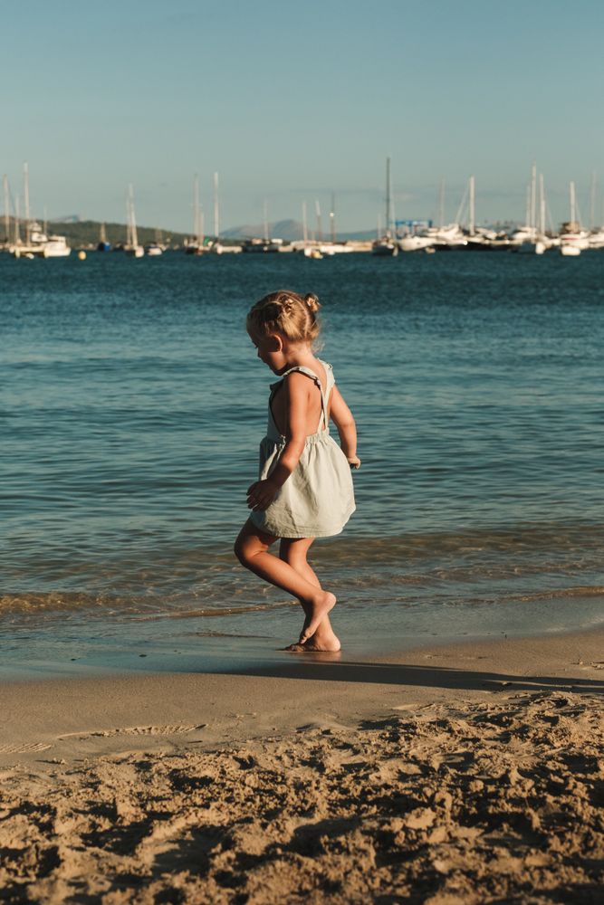 Blond girl walking towards the sea with ships