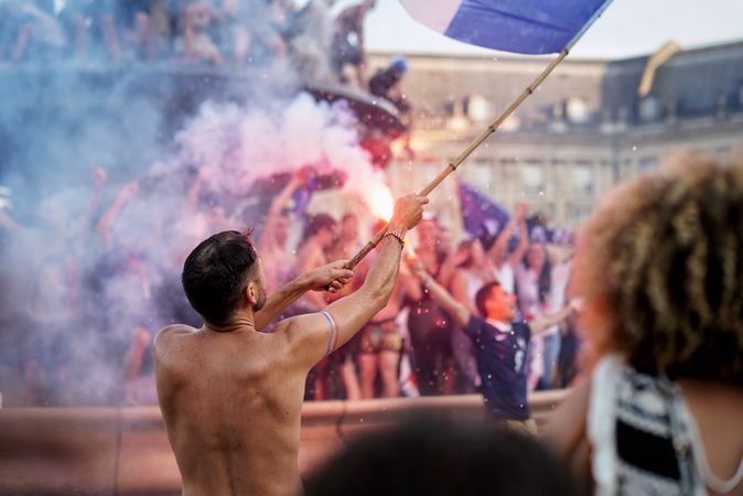 Man holding blue flag near crowd at festival