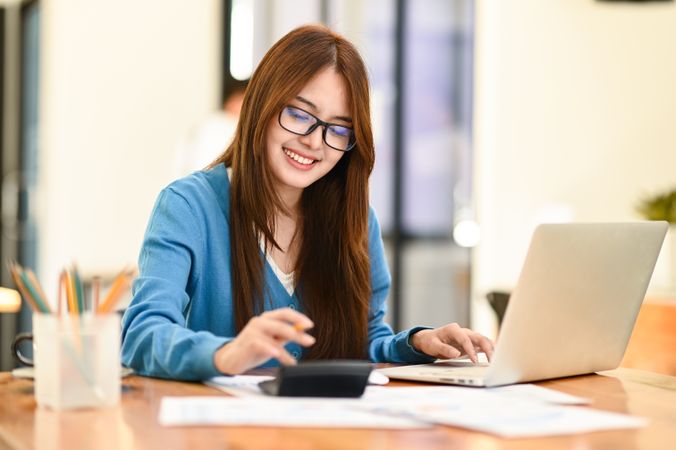 A woman working with laptop and calculator.