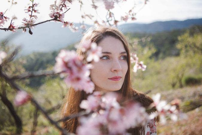Young happy woman between trees in garden