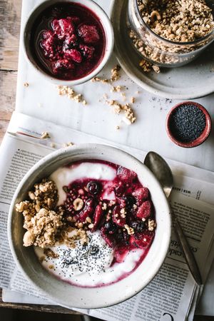 Delicious breakfast bowl with quinoa, rice and groats near tea cup and newspaper