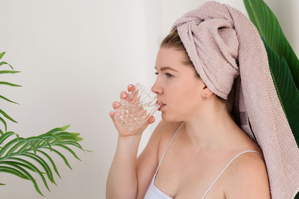 Woman drinking water after skincare.