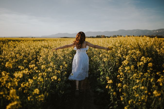 Anonymous woman walking in flower field