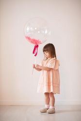 Studio shot of girl in pink dress holding standing