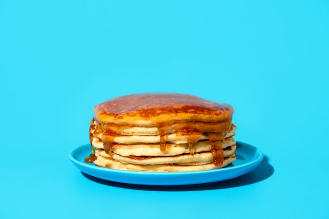 Homemade pancakes with syrup isolated on a blue background