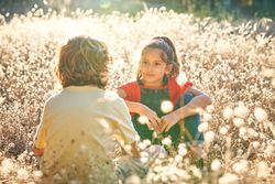 Girl looking at brother sitting near flowers