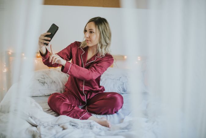 Woman sitting in bed with smartphone,