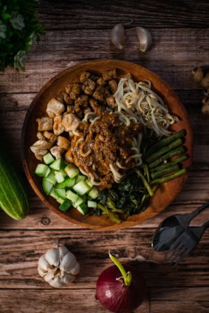 A plate of food with noodles and vegetables on a wooden table.