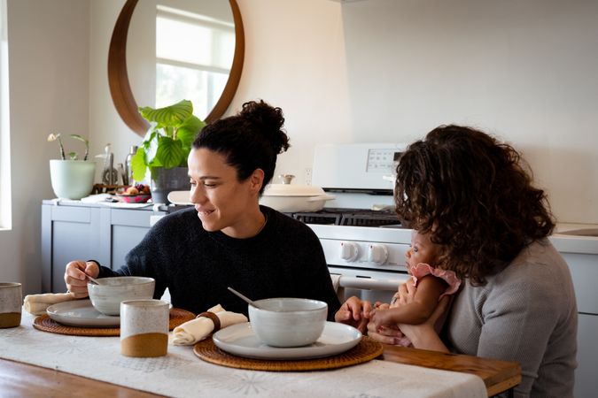 Two women eating soup with baby at their dining table