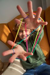 Delightful boy with multicolored strings on fingers