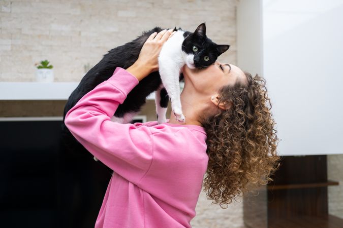 Woman raising up and kissing cute cat