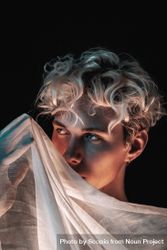 Portrait of blonde young man with textile against dark background 4AXY85