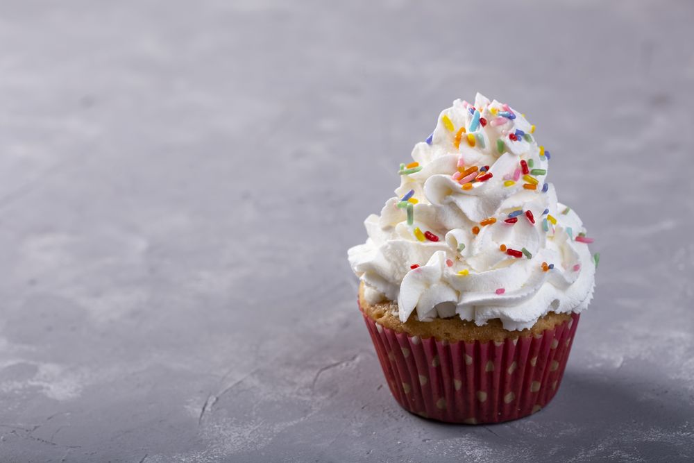 Tasty party cupcakes on the table. Cupcakes with whipped cream.