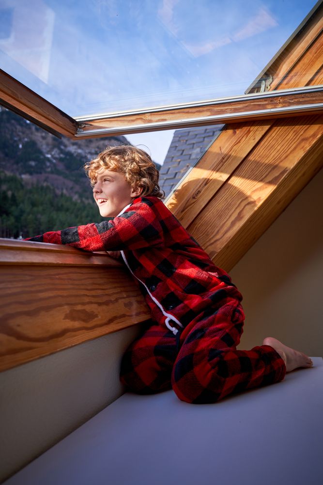 Smiling boy looking out window in mountain hotel