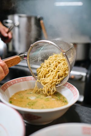 Crop person making ramen in kitchen